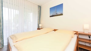 Een hotelkamer met een bed, nachtkastje, lamp en een schilderij aan de muur.