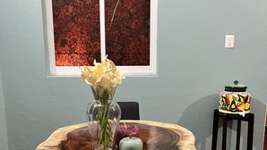 Une table à manger dotée d’un plateau en bois original, un vase rempli de fleurs et une pomme décorative.