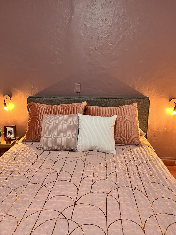 A bedroom with a bed, pillows, a nightstand, and wall-mounted lights.