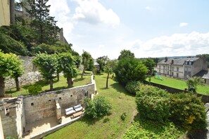 A courtyard with stone walls, a grassy area, and a playground. - Les Destinées - Bed and breakfast (Chinon)