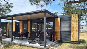 Un área de comedor moderna al aire libre con un porche cubierto, detalles de madera y vistas del paisaje circundante.
