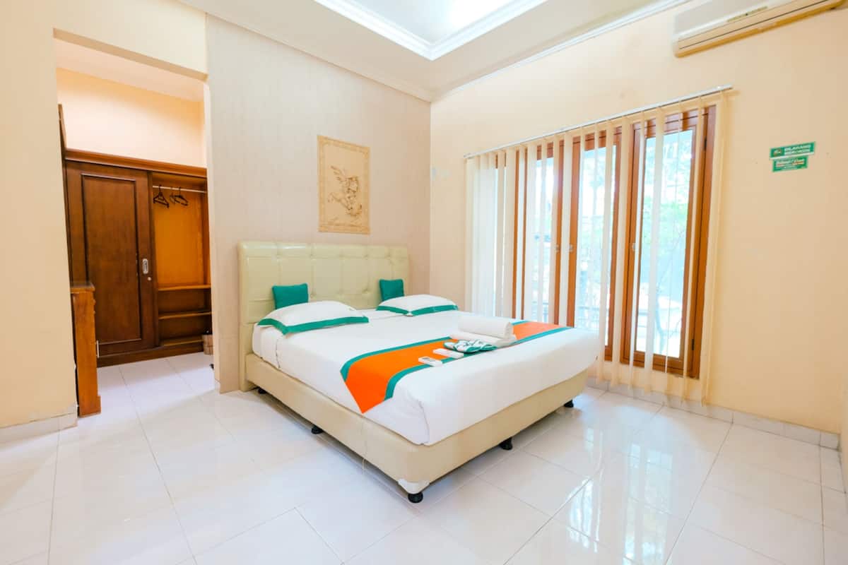 Una habitación de hotel con una cama, un armario, una ventana con persianas y un cartel en la pared.