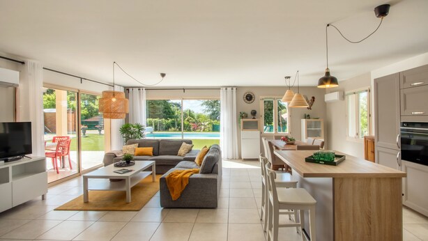 A modern kitchen with white cabinets, a wooden island, and a dining area with a table and chairs.