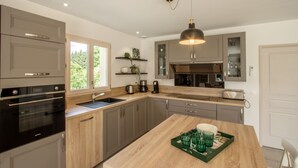A modern kitchen with wooden cabinets, a built-in oven, a sink, and a dining area with a wooden table.