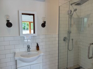 A bathroom with a white sink, a mirror, and a glass-enclosed shower.