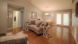 Ein geräumiges Wohnzimmer mit Deckenventilator, einer Couch, einem Couchtisch und einem Essbereich mit Tisch und Stühlen.