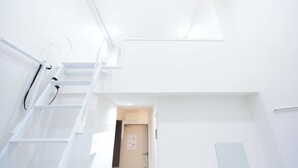 A bright, white interior with a staircase leading to an upper level. - Studio G2 (Tokyo)