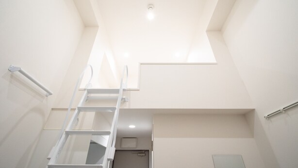 A narrow, white-walled room with a skylight, a white ladder, and a small door. - Studio G2 (Tokyo)