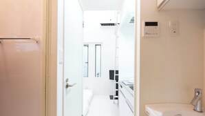 A modern bathroom with a white sink, a mirror, and a shower area. - Studio G2 (Tokyo)