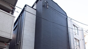 A modern building with a dark facade, a visible entrance, and a sign indicating it is a hotel. - Studio G2 (Tokyo)