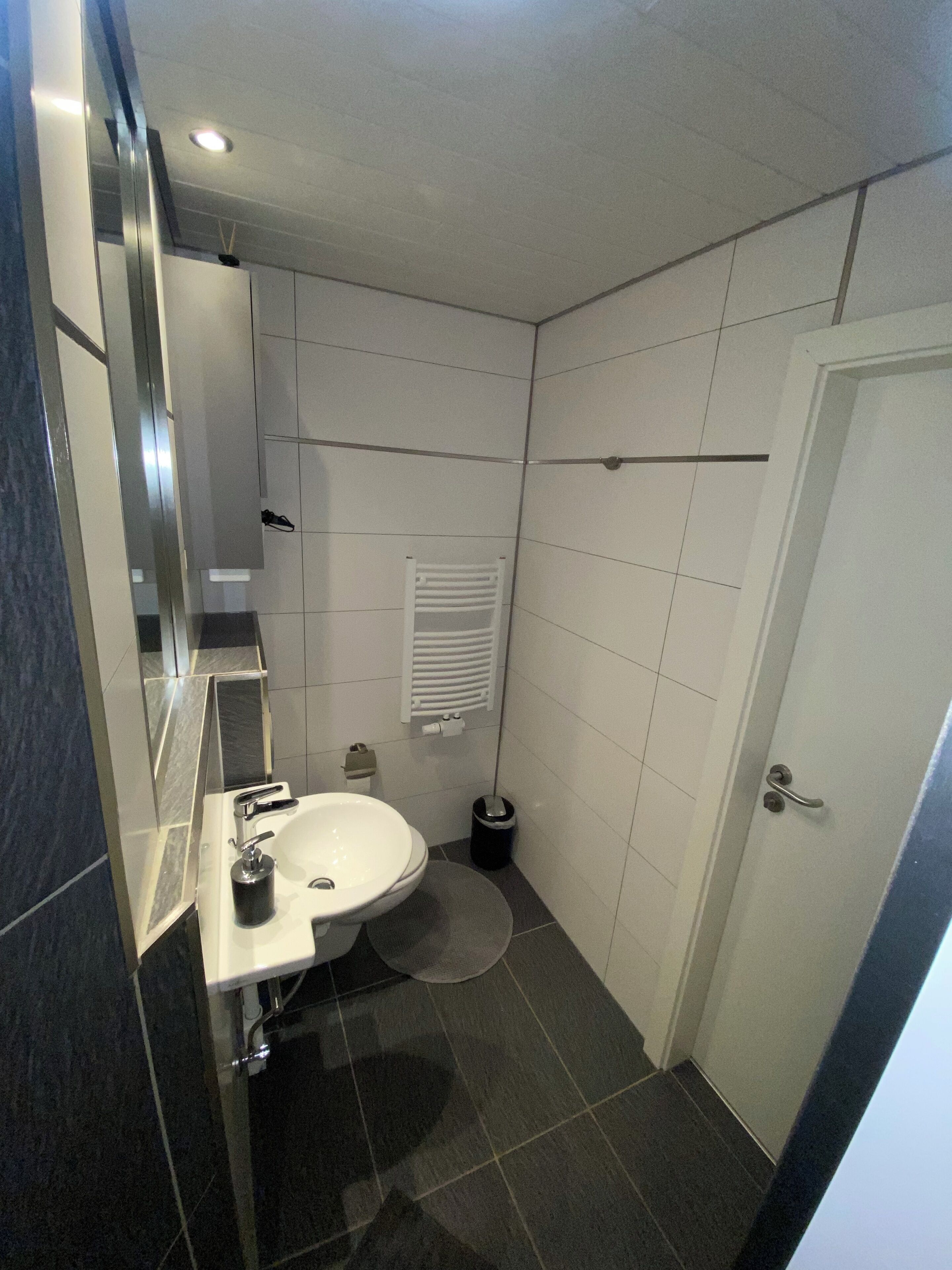 A bathroom with a white sink, mirror, and tiled walls.