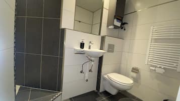 Een moderne badkamer met toilet, wastafel en douche.