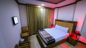 A hotel room with a bed, bedside lamps, a desk, and a chair. - Mid Town Hotel (Islamabad)
