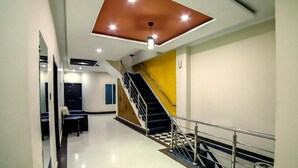 A modern hotel lobby with a staircase, a checkered floor, and a ceiling with recessed lighting. - Mid Town Hotel (Islamabad)