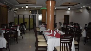 A restaurant with multiple tables and chairs, each set with white tablecloths and red placemats. - Mid Town Hotel (Islamabad)