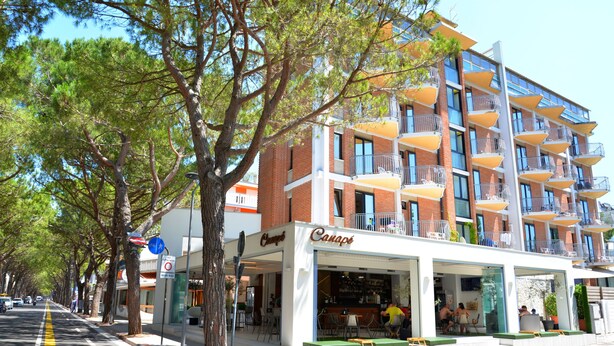 Un hôtel à plusieurs étages doté d’une terrasse, d’un bar bien visible et offrant une vue sur un ciel dégagé.