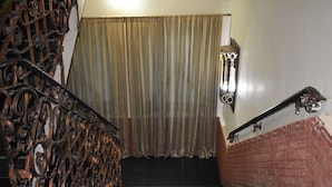 A staircase with ornate metal railings and a brick wall. - Undrah Inn Hotel (New Mirpur City)