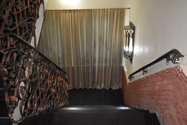 Una escalera con barandillas metálicas ornamentadas y un muro de ladrillo.