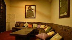 A cozy living room with a sofa, a coffee table, and a framed picture on the wall. - Undrah Inn Hotel (New Mirpur City)
