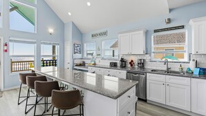 Une cuisine moderne avec des meubles blancs, un plan de travail en granit et un coin bar avec des tabourets.