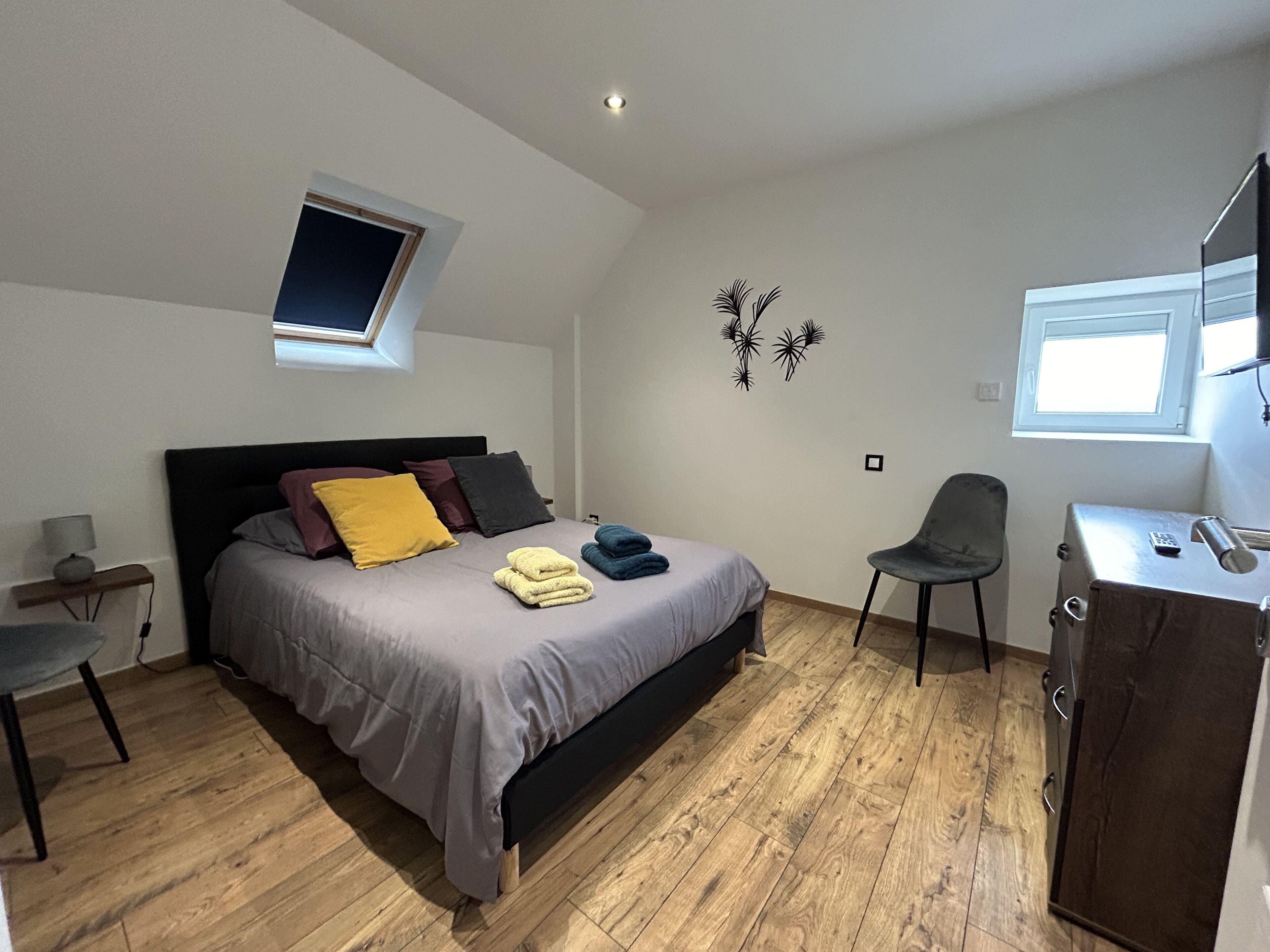 Une chambre à coucher moderne avec un lit, un bureau, une chaise et une petite fenêtre.