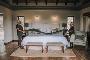 A bedroom with a large bed, two bedside tables, a chair, and a window. - Waterbuck Lodge (Hoedspruit)