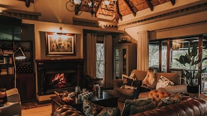 Una sala de estar acogedora con chimenea, sofás de cuero, una mesita de centro y una estantería.