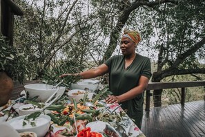 An outdoor dining area with a table set for a meal, surrounded by trees. - Waterbuck Lodge (Hoedspruit)