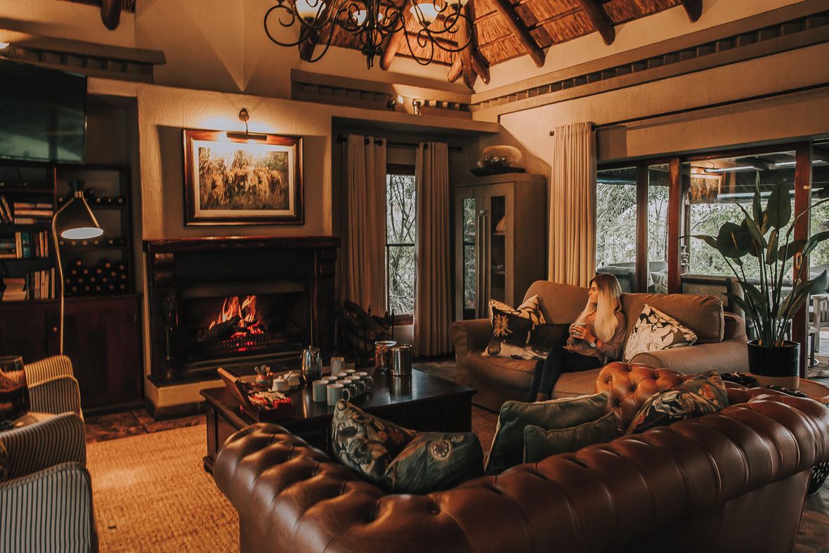 A cozy living room with a fireplace, leather sofas, a coffee table, and a bookshelf.