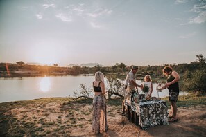 A group of people around a table by a lake at sunset. - Waterbuck Lodge (Hoedspruit)