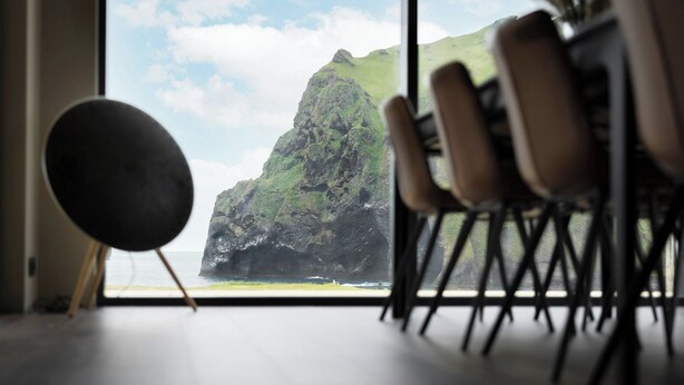 A room with a large window overlooking a mountainous coastline. - Luxury Ocean Villas (Vestmannaeyjar)
