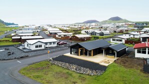 A residential area with modern houses, a road, and a view of distant hills. - Luxury Ocean Villas (Vestmannaeyjar)