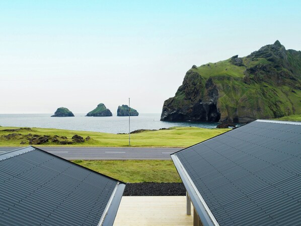 A coastal view with a road leading to a building with a metal roof.