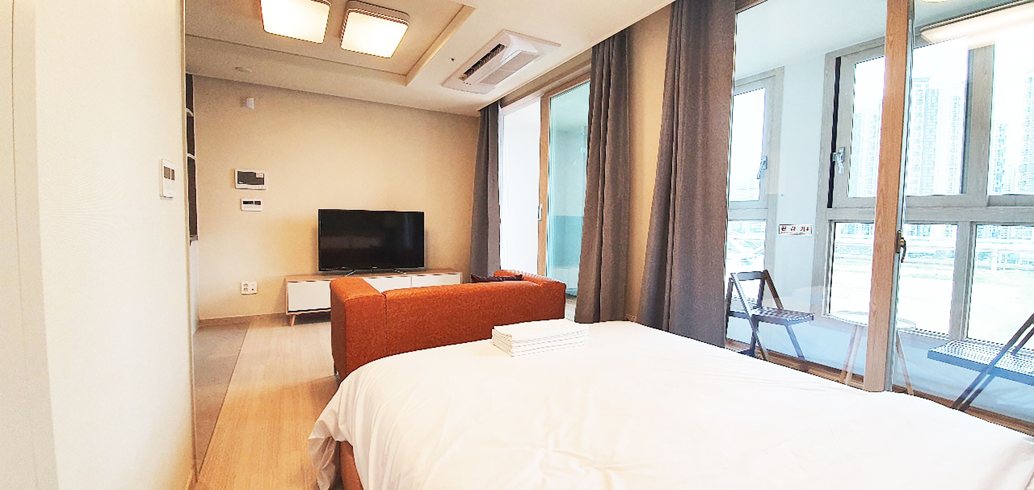 Ein Hotelzimmer mit Bett, Fernseher, Sitzecke und großen Fenstern.