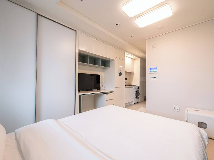 Quarto de hotel moderno com cama, escrivaninha e máquina de lavar.