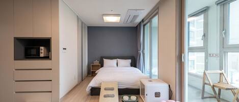 Een moderne slaapkamer met een bed, inbouwkast, nachtkastjes, een mand voor huisdieren en een raam met uitzicht.