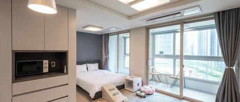 Quarto de hotel moderno com uma cama, poltrona de massagem, mesa pequena com velas e vista da cidade através de grandes janelas.