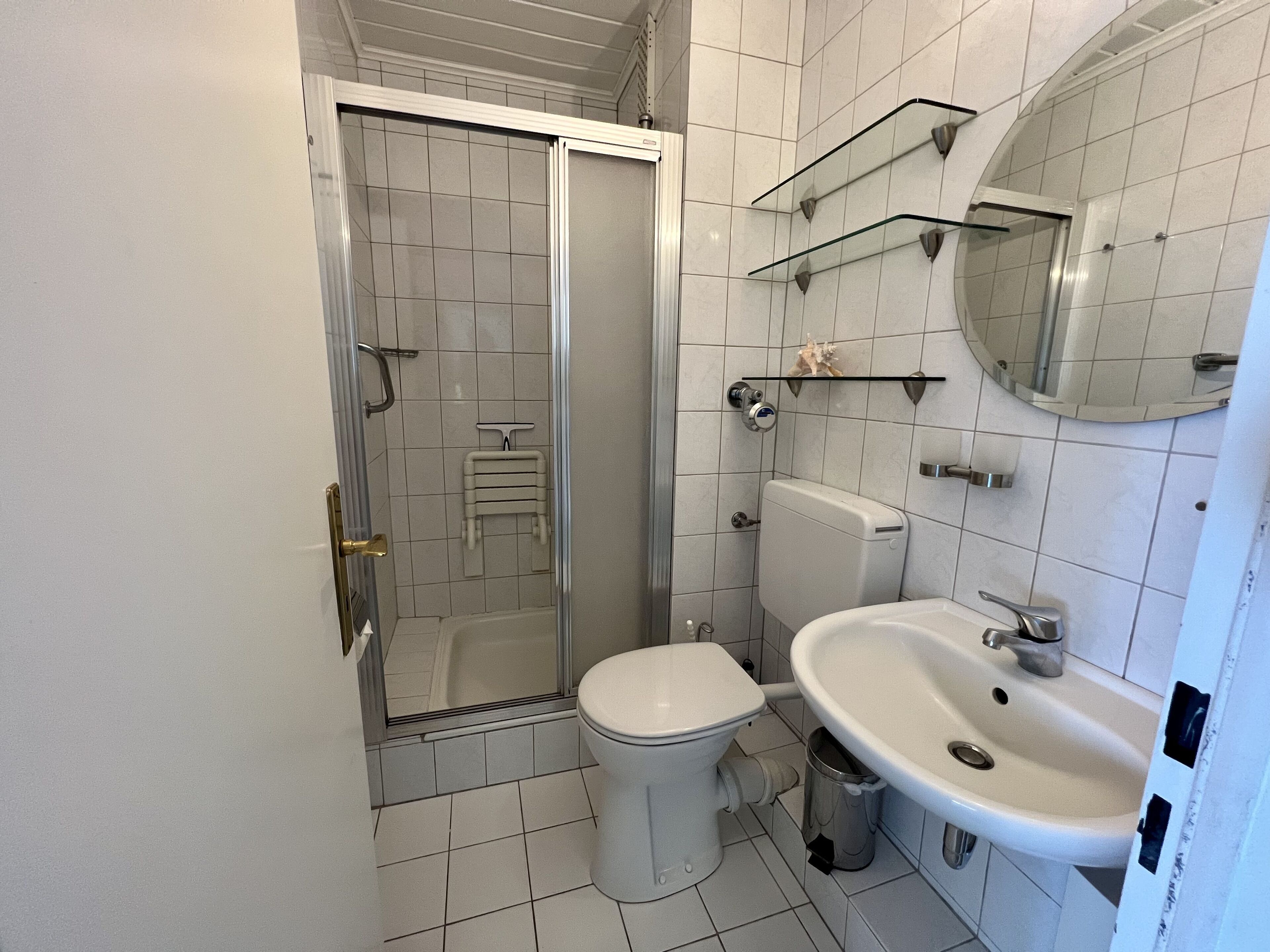 A bathroom with a toilet, sink, and glass shower enclosure.