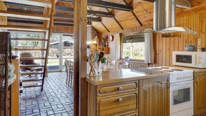 Cucina in legno con piano cottura, microonde e zona pranzo con sedie e tavolo.