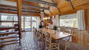 Un interno in legno con zona pranzo, camino e ampie finestre.