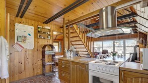 Cucina di una baita in legno con piano cottura, lavello e pensili in legno.