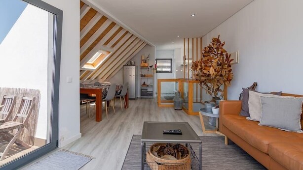 Ein modernes Wohnzimmer mit einer Couch, einem Couchtisch und einem Essbereich mit Stühlen und einem Tisch.