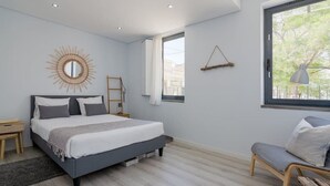 Ein Schlafzimmer mit Bett, Nachttischen, einem Fenster mit Blick und einer Wandlampe.