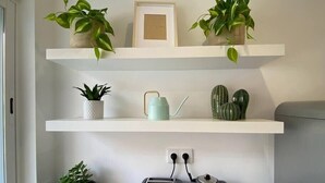 A kitchen with white shelves holding plants, a kettle, and a toaster. - Project Montalvão, Setúbal (Setúbal)