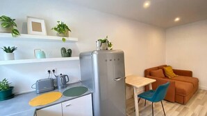 A compact kitchen with a refrigerator, a sink, and a small dining area with a table and chairs. - Project Montalvão, Setúbal (Setúbal)