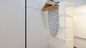 A white wall with a geometric wall art piece and a white shelving unit. - Setúbal Downtown Blue 0 (Setúbal)