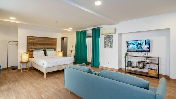 A modern hotel room with a bed, a sofa, a TV, and a small shelf with decorative items. - Setúbal Downtown Blue 0 (Setúbal)