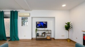 A living room with a flat-screen TV mounted on the wall, a wooden floor, and a blue sofa. - Setúbal Downtown Blue 0 (Setúbal)
