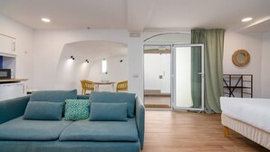 A modern, well-lit room with a sofa, a bed, a dining area, and a kitchen area. - Setúbal Downtown Blue 0 (Setúbal)