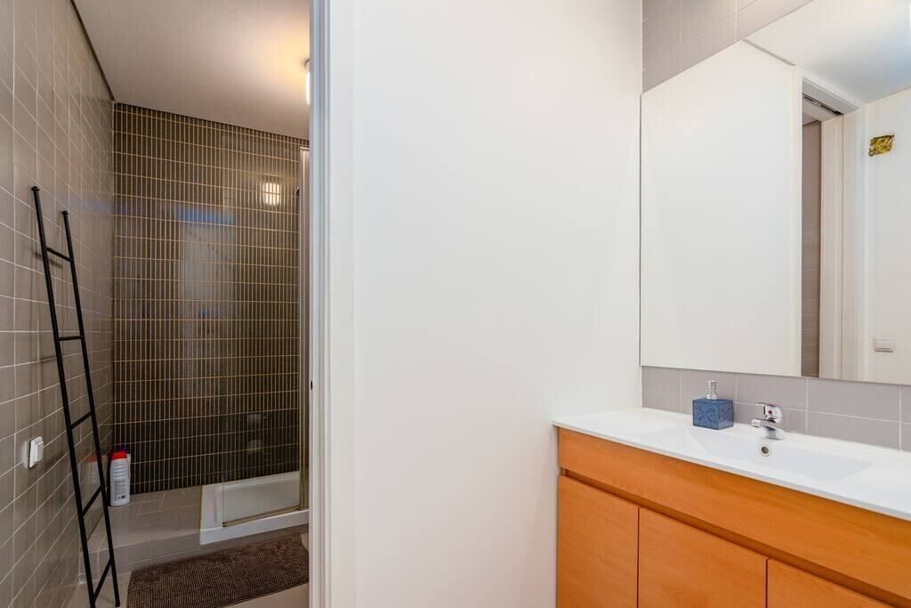 A bathroom with a shower, a sink, and a mirror.